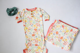 Floral baby outfit with matching blanket on a light gray background
