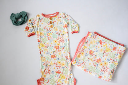 Floral baby outfit with matching blanket on a light gray background