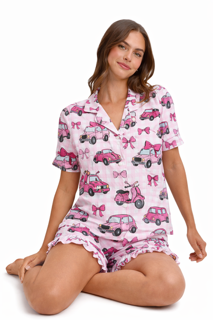 Woman wearing a pink pajama set with car and bow pattern on a white background