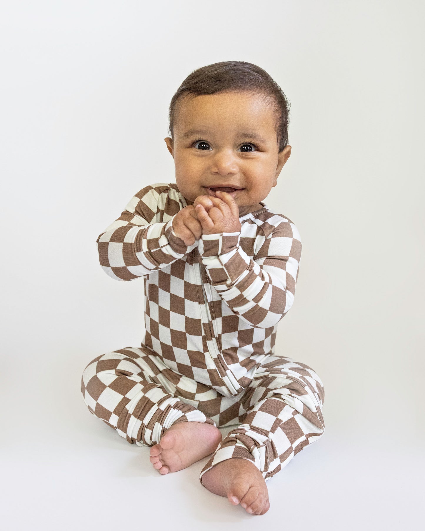 Baby wearing a brown and white checkered outfit on a white background