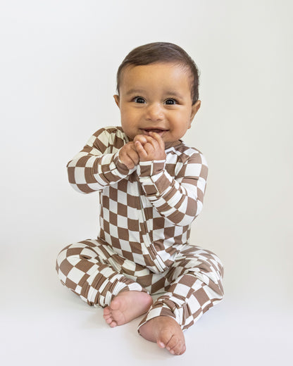 Baby wearing a brown and white checkered outfit on a white background