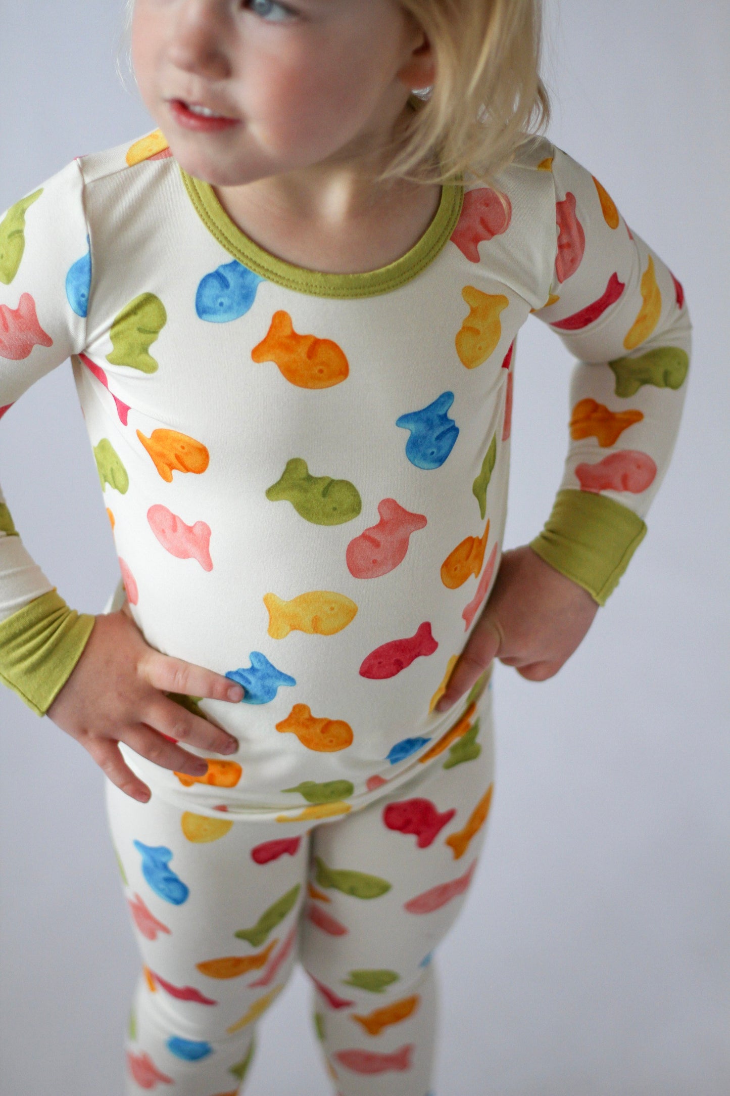 Child wearing a colorful fish-patterned onesie against a plain background
