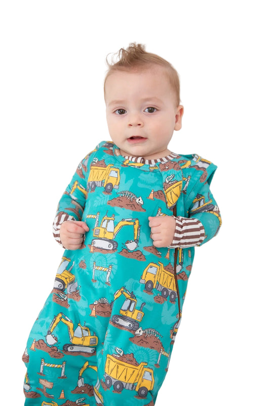 Baby wearing a teal onesie with construction vehicle prints on a white background