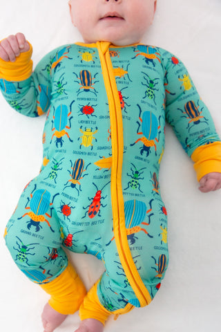 Baby wearing a colorful insect-themed onesie on a white background