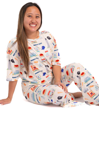 Woman wearing colorful pajamas with a pattern of various items on a white background