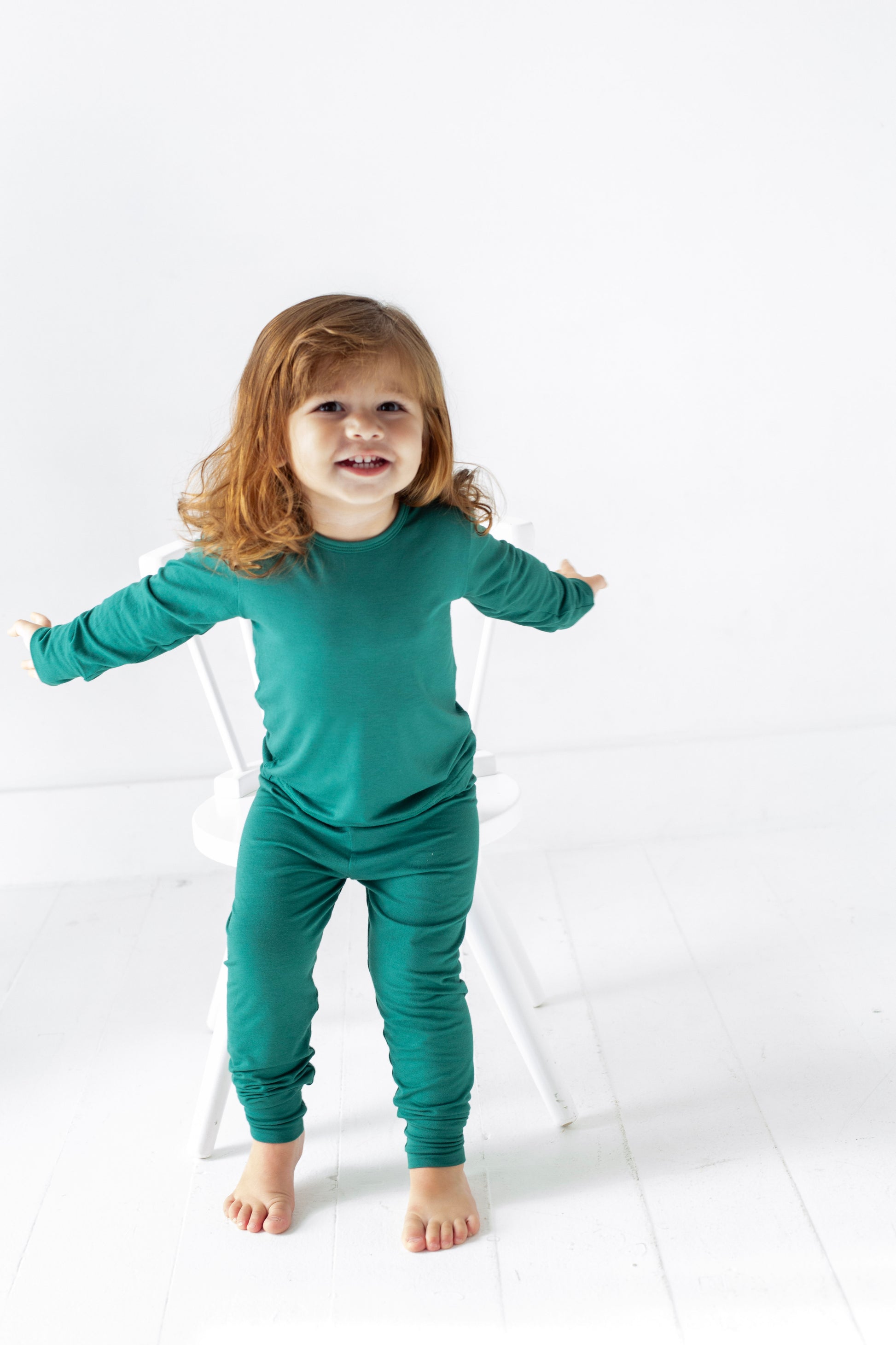 Child wearing teal pajamas standing on a white background