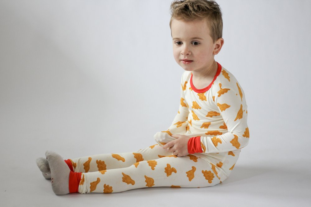 Child wearing a white outfit with orange patterns on a plain background
