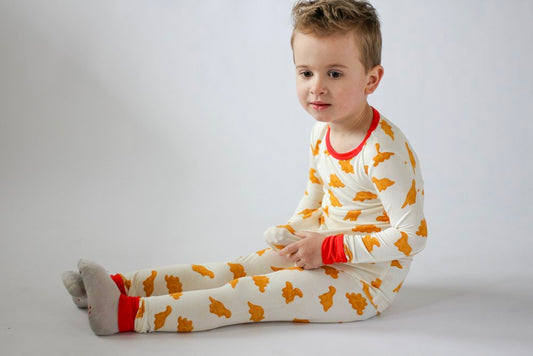 Child wearing a white outfit with orange patterns on a plain background