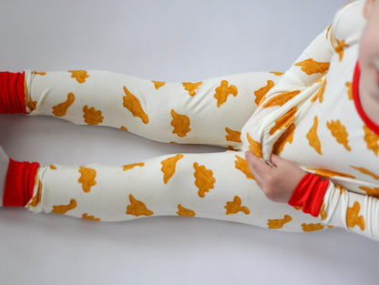 White leggings with orange patterns worn by a child on a light gray background