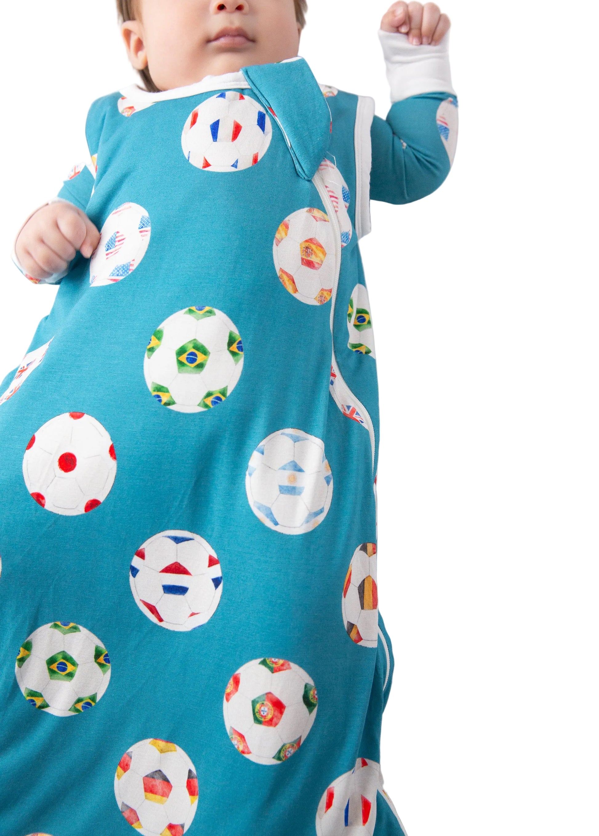 Baby wearing a blue onesie with colorful soccer ball patterns on a white background