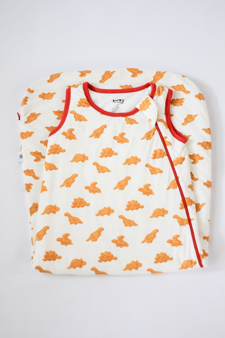 Children's long-sleeve shirt with orange dinosaur pattern on a white background