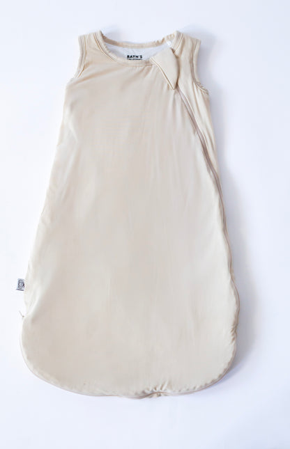 Beige baby sleeping bag with a bow on a white background