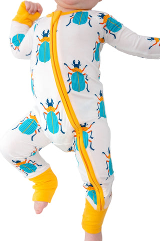 Baby wearing a onesie with beetle pattern and yellow accents on a white background