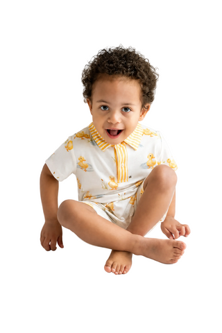 Child wearing a white outfit with yellow accents on a light gray background