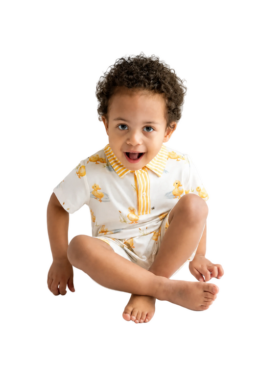 Child wearing a white outfit with yellow accents on a light gray background