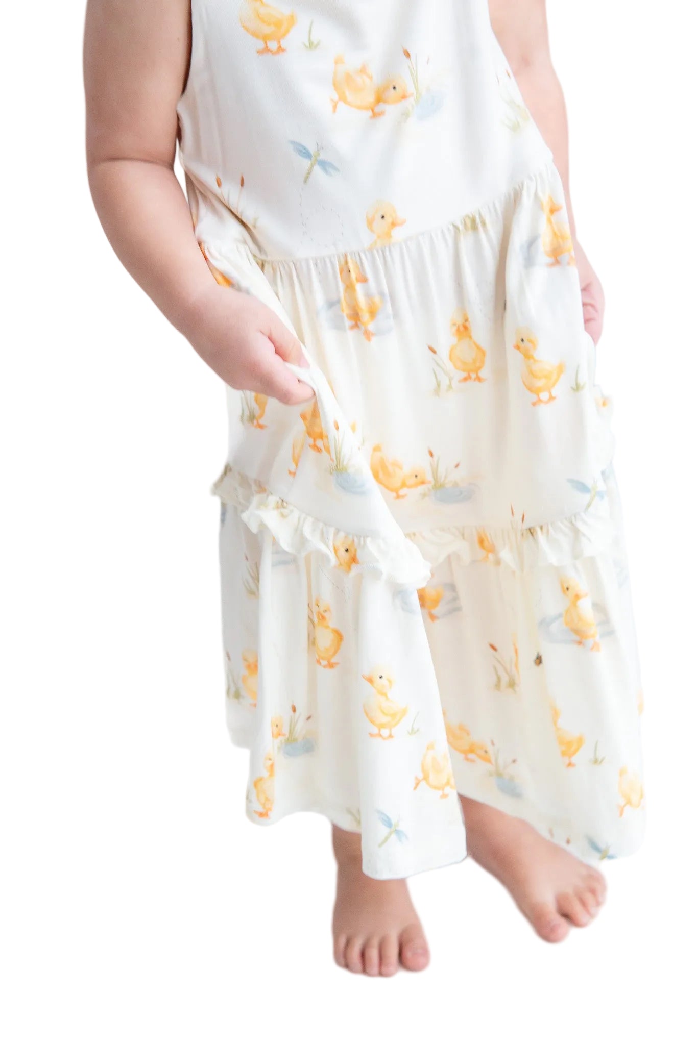 Child wearing a white dress with yellow floral patterns on a white background