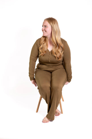 Woman wearing a brown outfit sitting on a chair against a white background