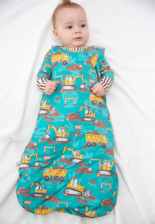 Baby wearing a colorful construction-themed sleep bag on a white background