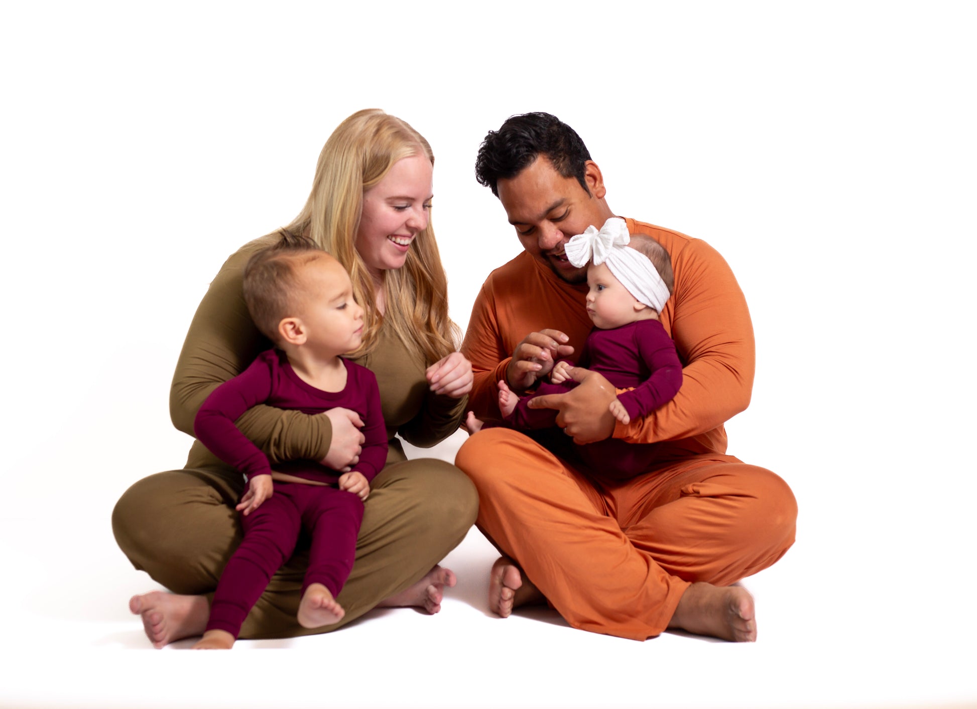 Family of four sitting together on a white background