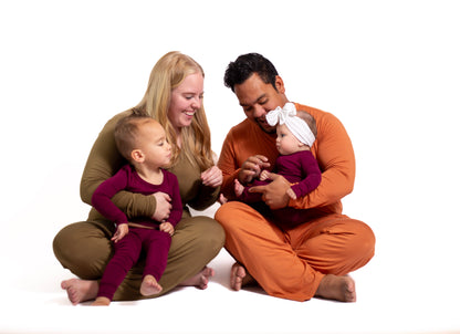 Family of four sitting together on a white background