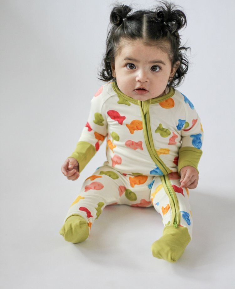 Child wearing a colorful fish-patterned onesie on a plain background