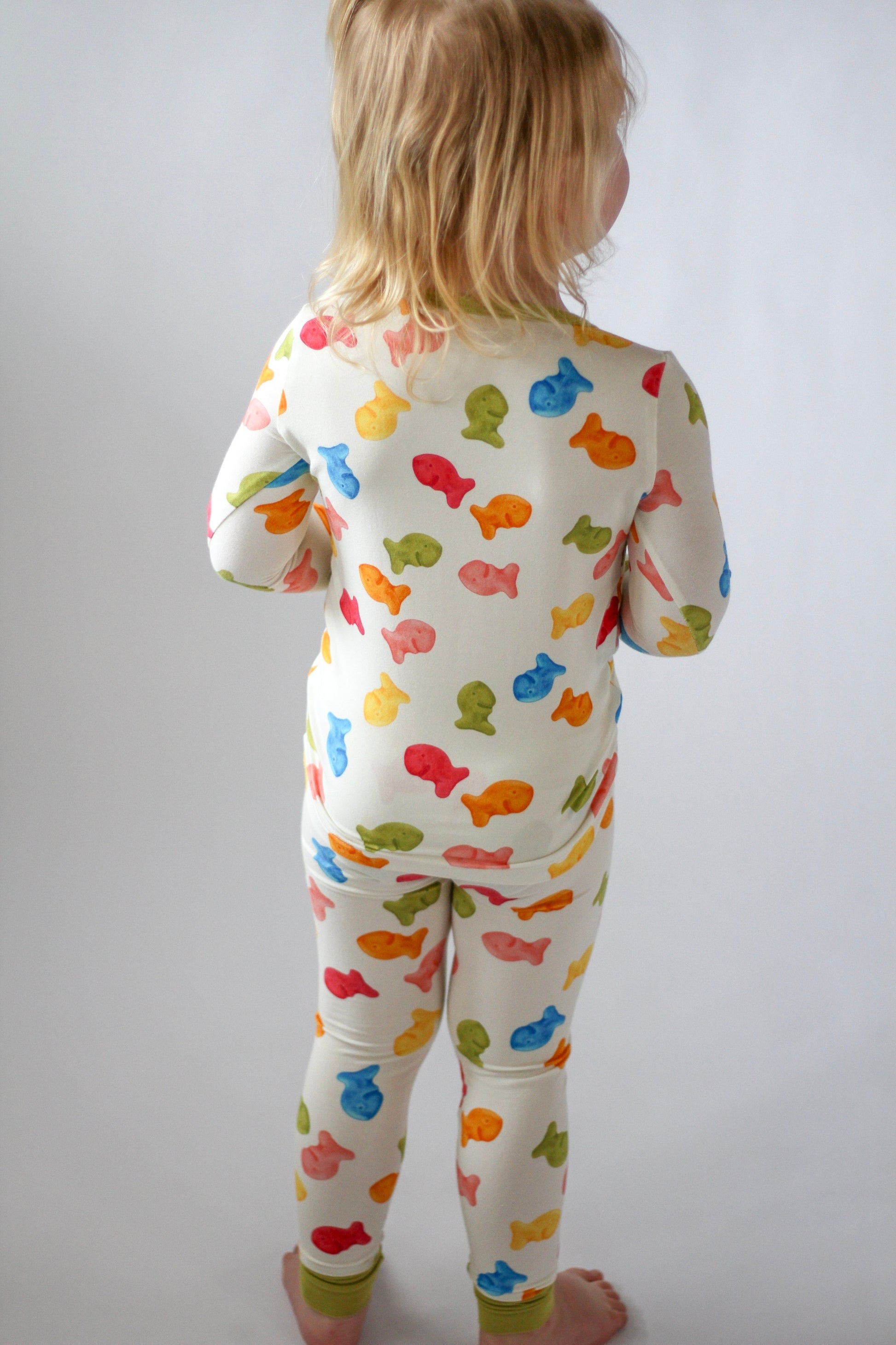 Child wearing a colorful fish-patterned onesie against a plain background