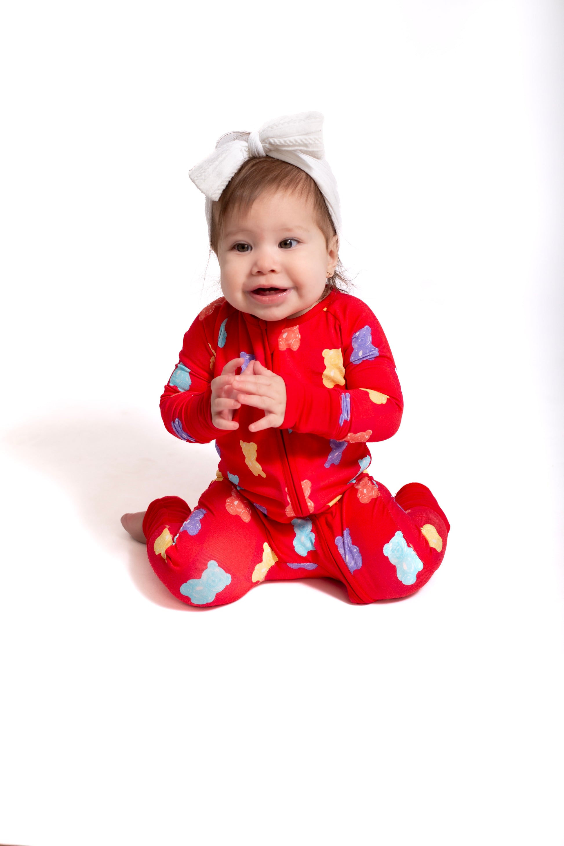 Baby wearing a red outfit with colorful patterns on a white background