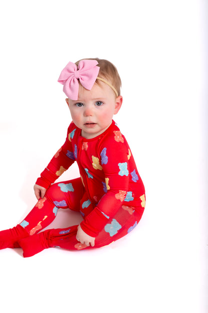 Baby in a red outfit with butterfly patterns sitting on a white background