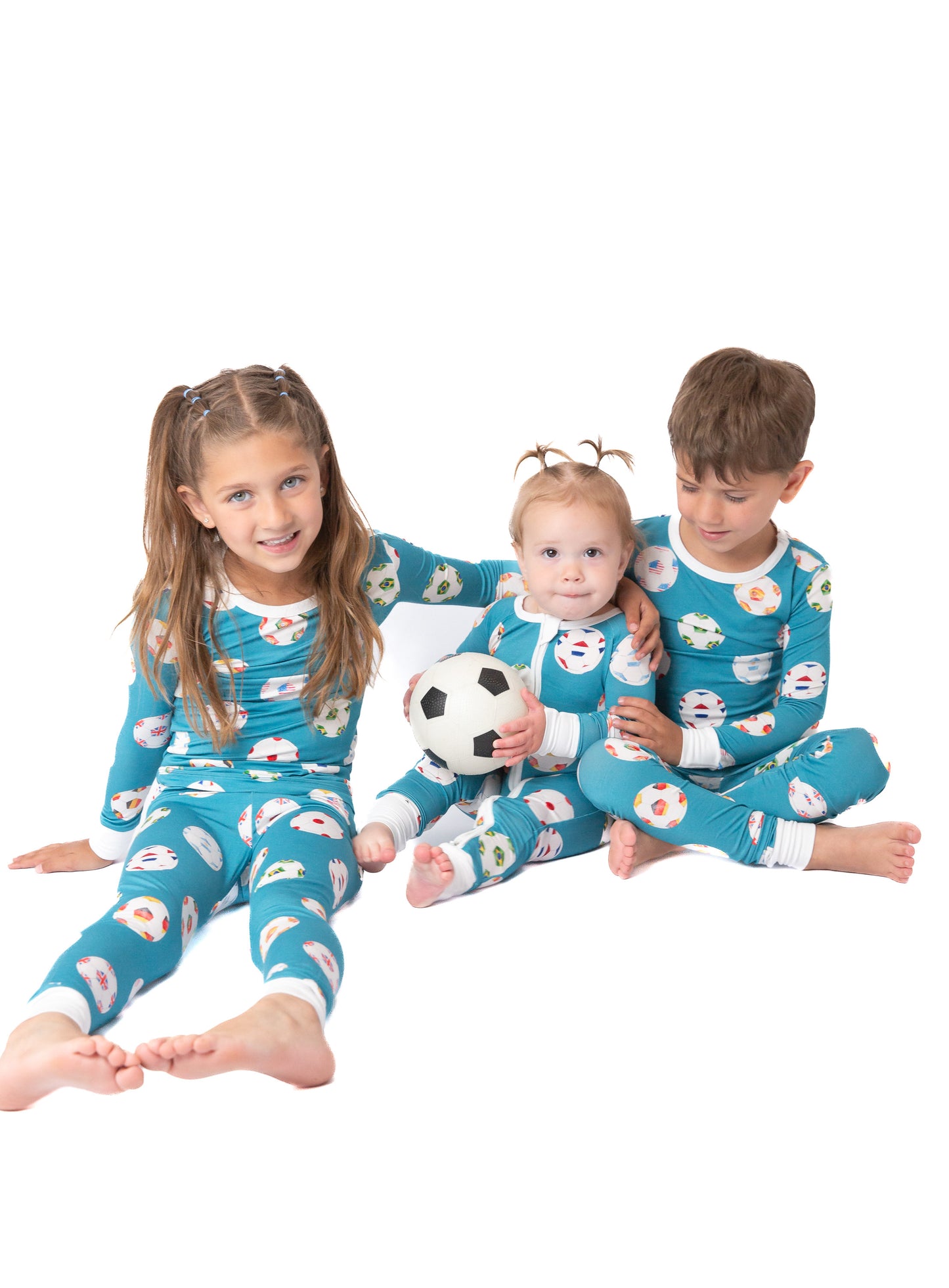 Three children wearing matching blue pajamas with a snowman pattern on a white background.