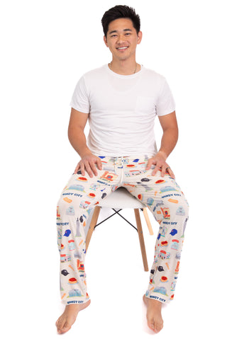 Man wearing colorful pajama pants sitting on a chair against a white background
