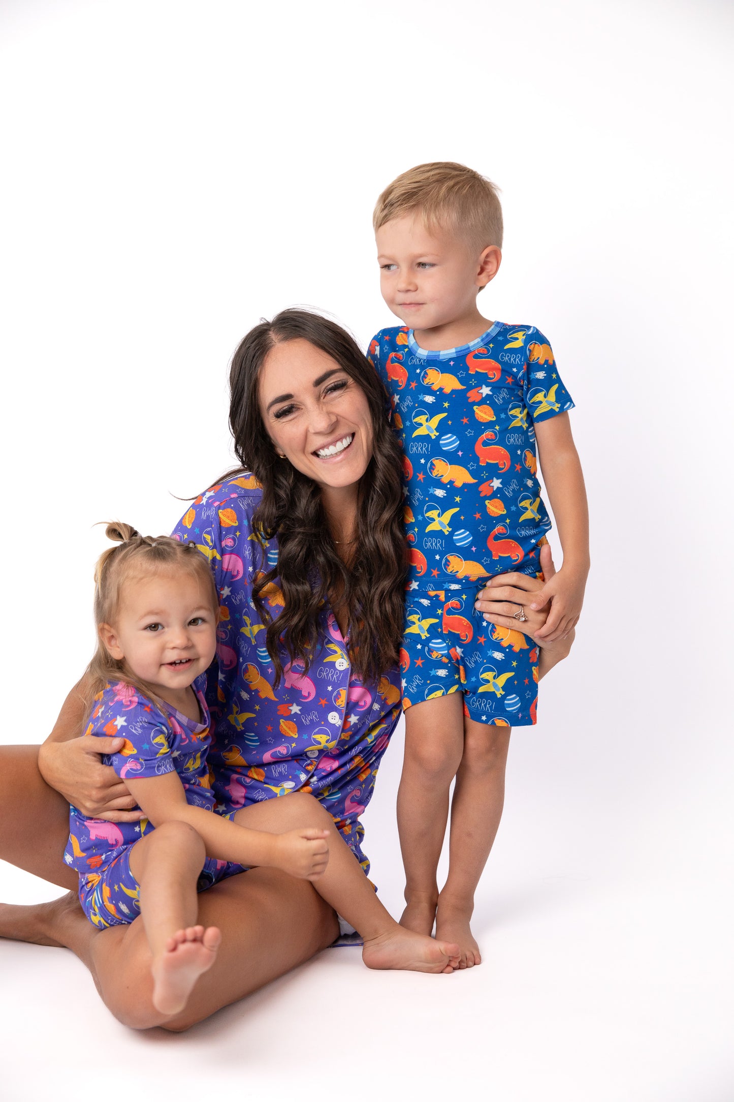 A woman and two children wearing matching short-sleeve pajama sets with a colorful fish pattern, posed against a clean white studio background.