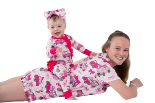 Woman and child wearing matching pink pajamas with cartoon characters on a white background
