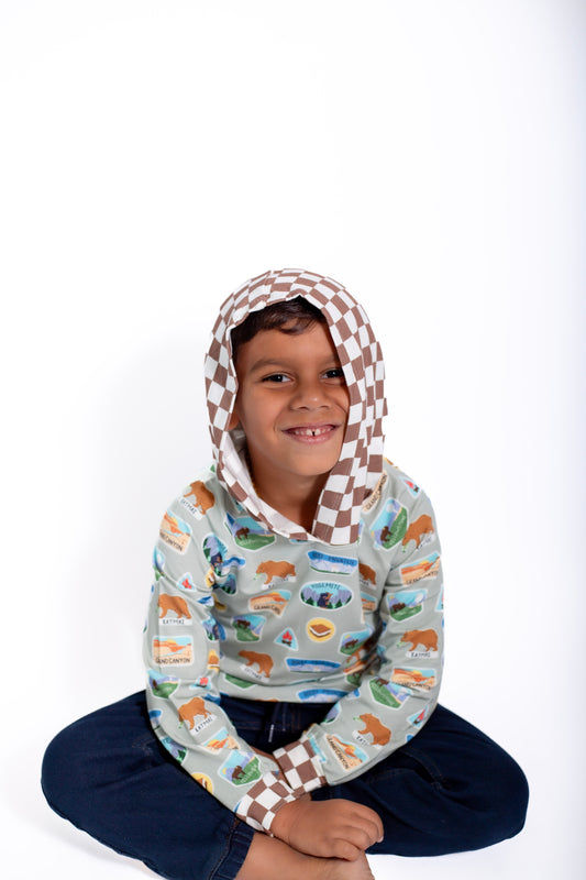 Child wearing a patterned hood and colorful shirt on a white background