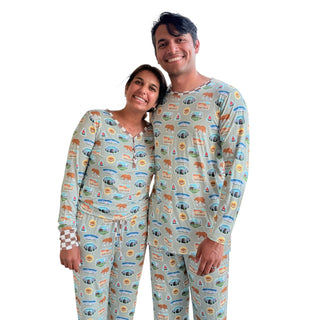Two people wearing matching pajama sets with a pattern of animals and nature on a white background.