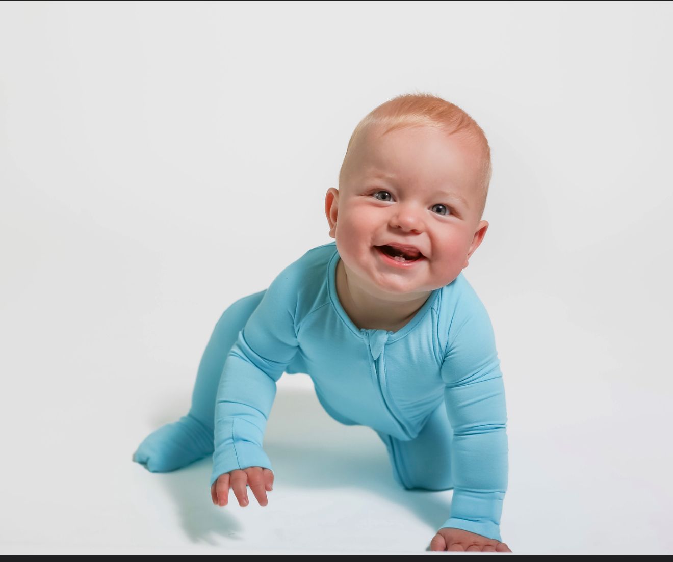 Baby in a blue onesie crawling on a white background