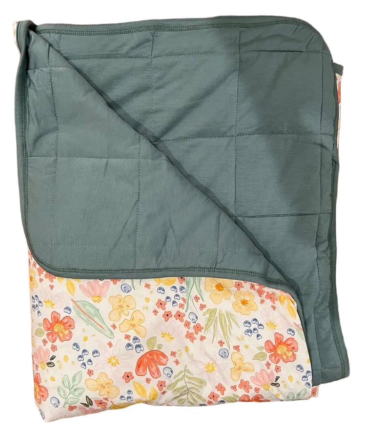 Green quilted blanket with floral pattern on a wooden surface