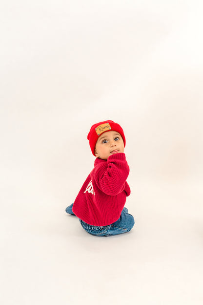 Child wearing a red sweater and hat on a white background