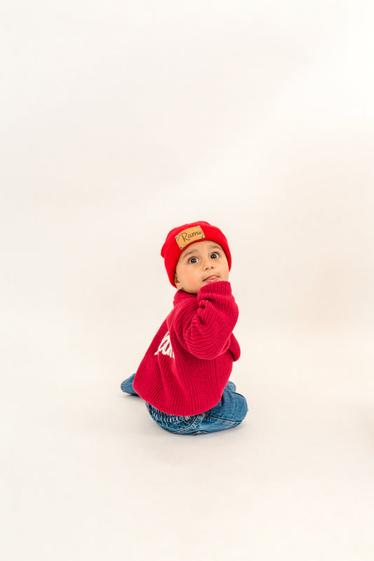 Child wearing a red sweater and hat on a white background