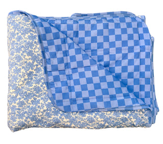 Folded blue and white checkered blanket on a beige floor.