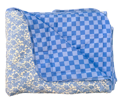 Folded blue and white checkered blanket on a beige floor.