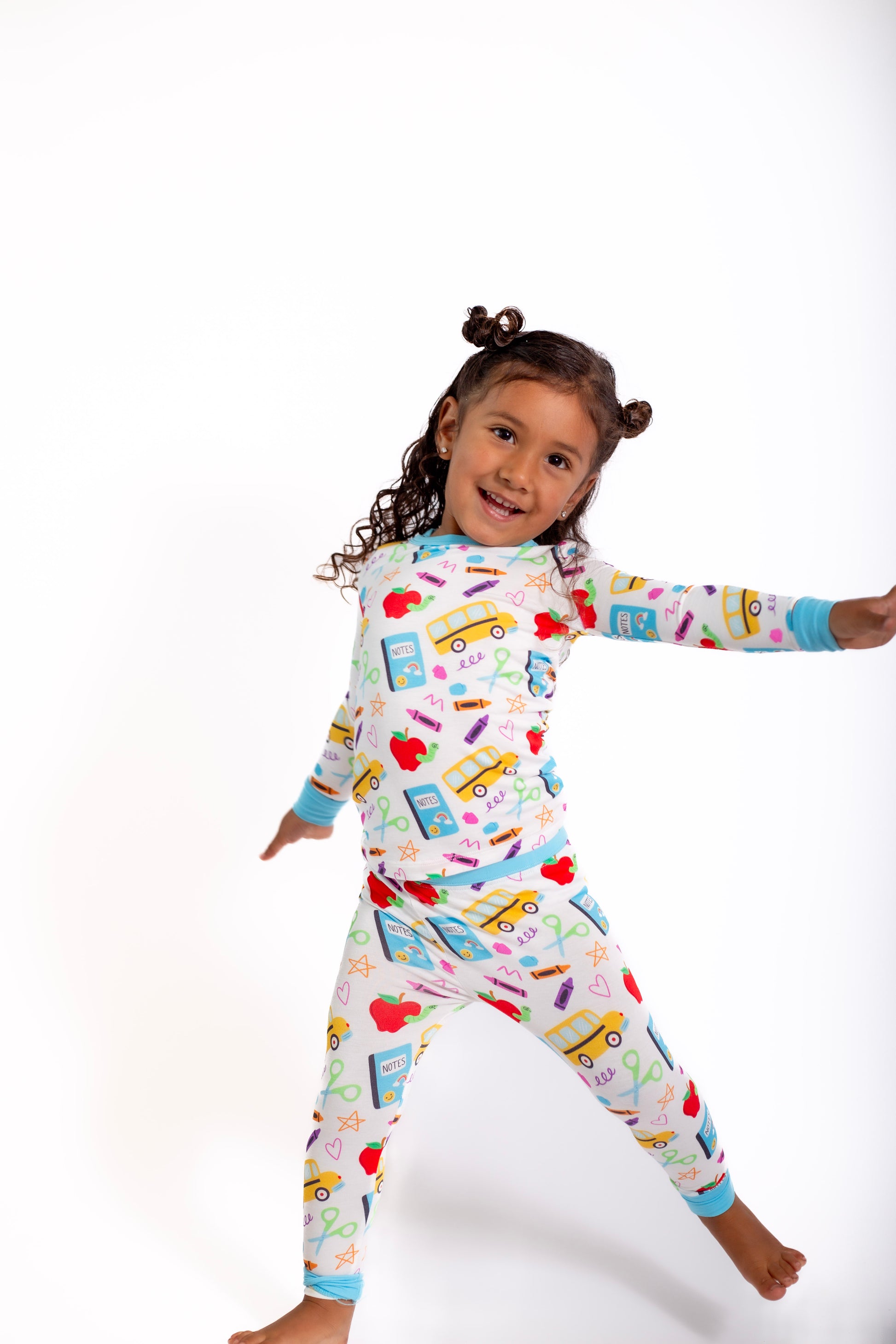 Child wearing a colorful pajama set with vehicle pattern on a white background