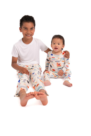 Two children wearing colorful pajamas sitting on a white background