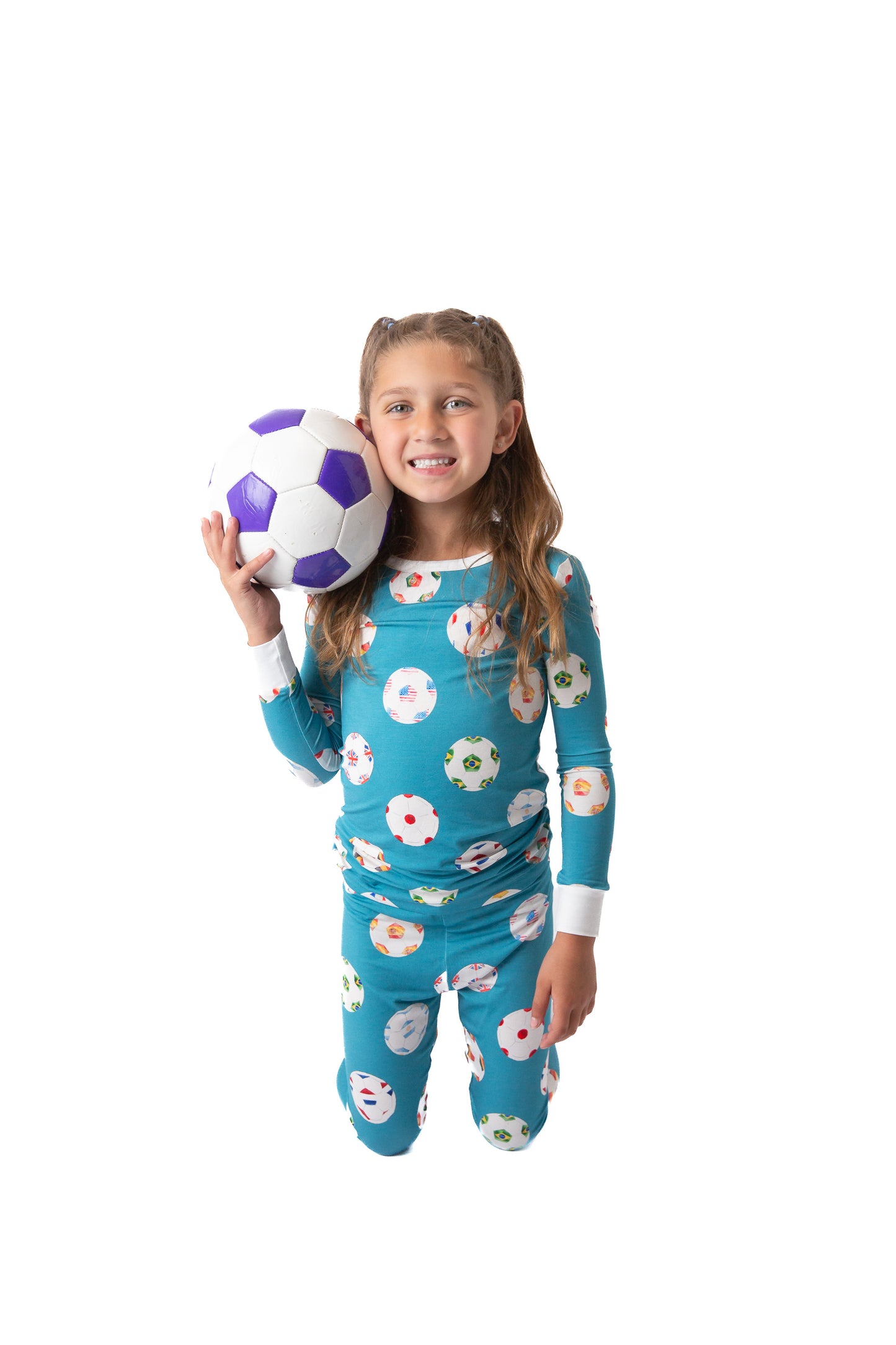 Child wearing a floral pajama set holding a soccer ball on a white background