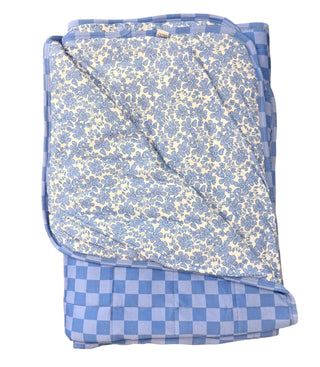 Folded blue and white checkered blanket on a beige carpet