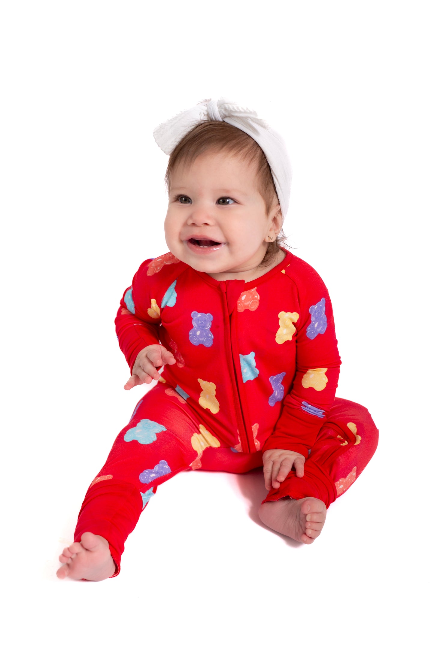 Baby wearing a red onesie with colorful bear patterns on a white background