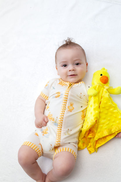 Baby in a yellow and white outfit with a duckling toy on a white background