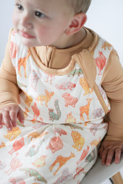 Baby wearing a patterned baby wrap with animal designs on a white background