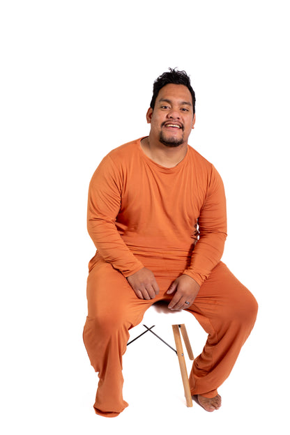 Man wearing an orange outfit sitting on a chair against a white background