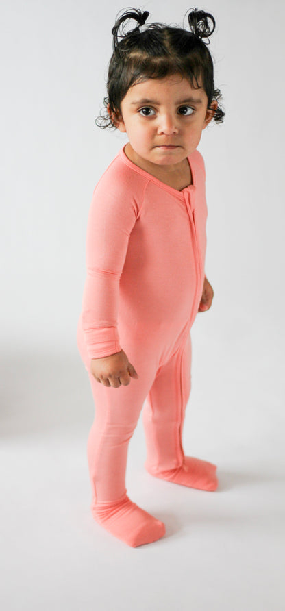 Child wearing a pink onesie against a white background
