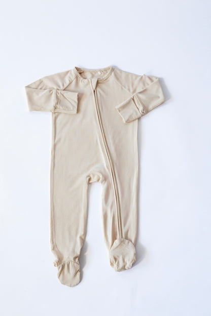 Beige baby onesie with bow details on a white background